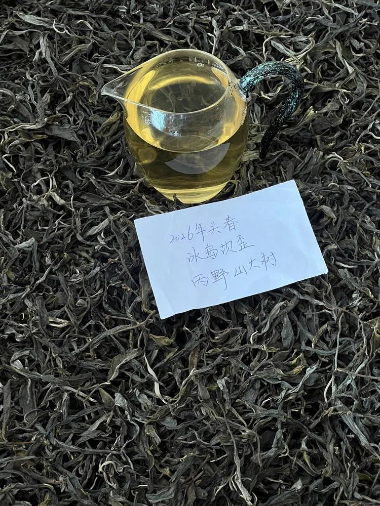 A glass pitcher of golden tea above dry leaves and a handwritten card