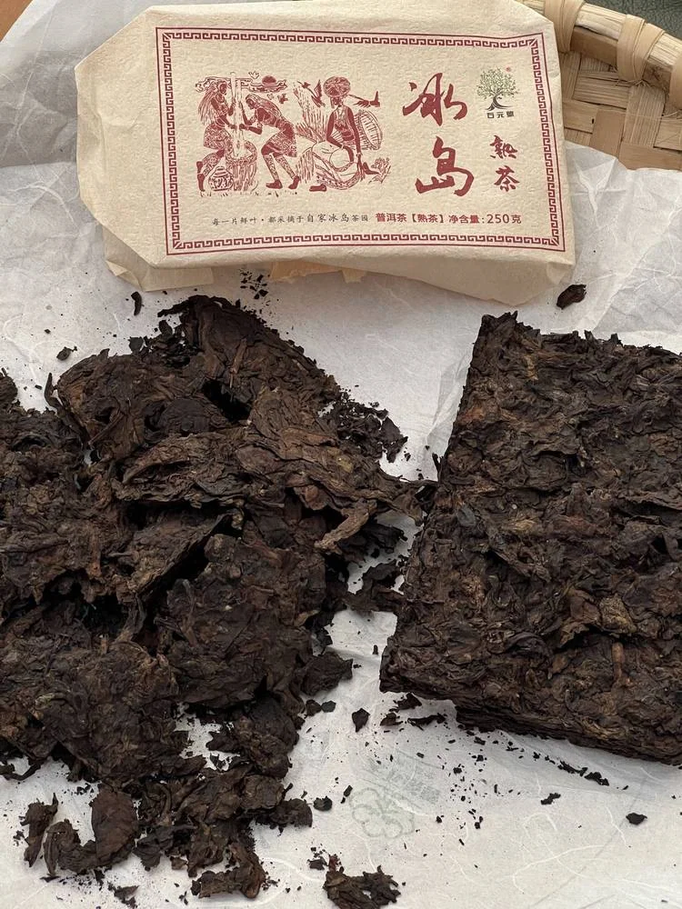 Opened dark tea brick on paper beside a wrapper labelled 冰岛熟茶 and 250 grams